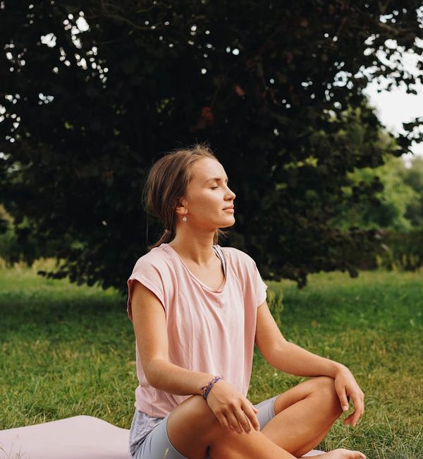 Person in a focused pose on a yoga mat outdoors.